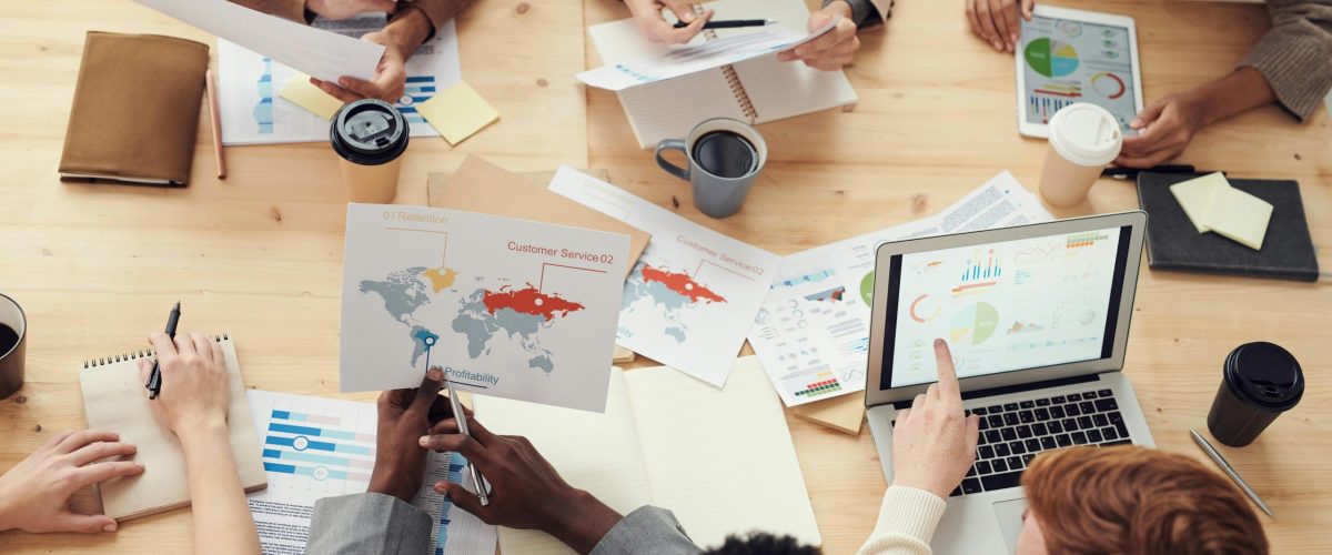 Diverse team engaging in a collaborative meeting with charts and laptops.